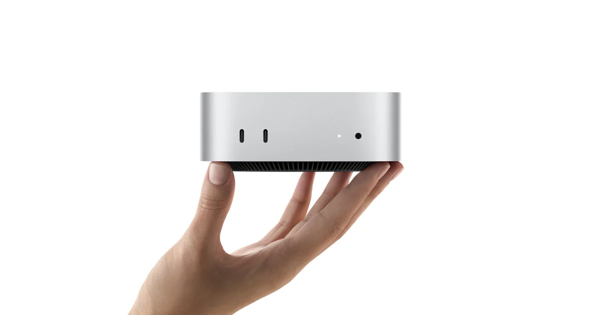 Silver Apple Mac mini M6 held in one hand and viewed from the front
